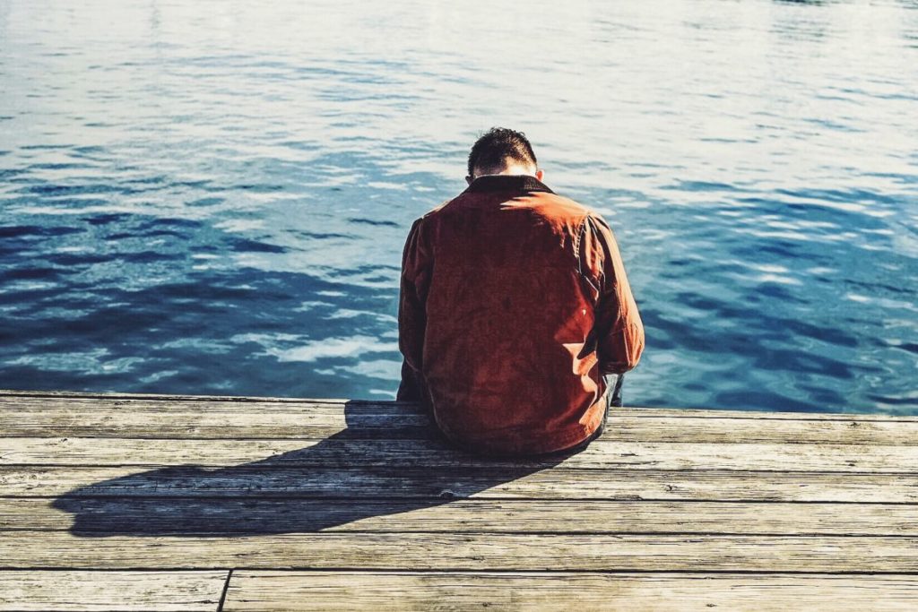 sad man on the dock thinking about how to let go of someone he loved